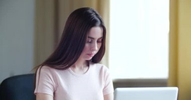 Yan görünümde genç bir kadın dizüstü bilgisayar kullanarak ekran daktilo mesajına bakıyor, bilgisayardaki sohbete odaklanmış bir kadın internette geziniyor sosyal medyada çalışıyor ya da evde online çalışıyor.