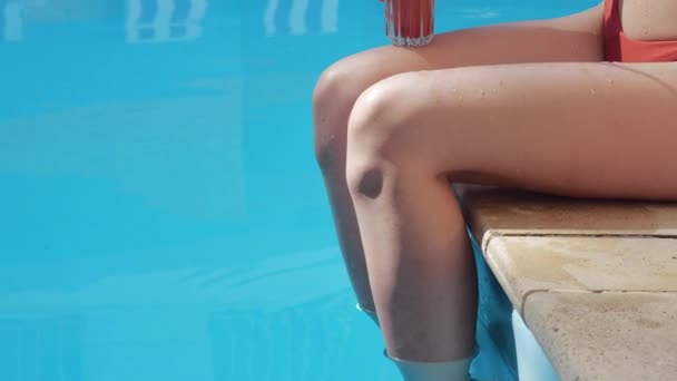 Close-up de molhado jovem corpo feminino na água movendo-se cortada tiro de menina sentado perto da piscina beber bebida saudável coquetel dieta, bronzeamento, uma menina mergulhando os pés pernas em água fria e descansando, relaxar — Vídeo de Stock