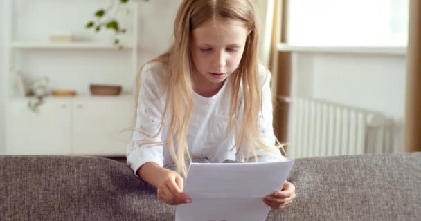 Liten skola flicka studier hemma i karantän under pandemi på e-learning, läser prov papper, ser positiv bra bedömning, glädjer framgång, hoppar glatt klappar händerna från segern — Stockvideo