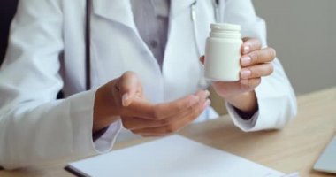 Kadın elinin tanınmayan hastaya haplı kavanozu uzattığı yakın plan. Kafkasyalı hasta adama ilaç veren bir doktor. Hekim, hastanede tedavi için ilaç tavsiyesi, sağlık konsepti
