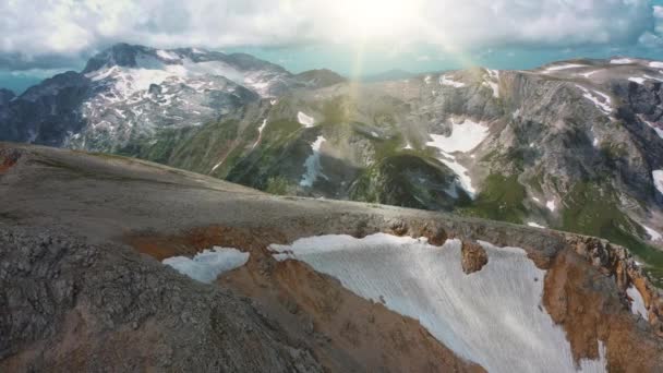 Uçan bulutlar ve yaz sabahı parlak güneş ışınları altında manzarada güzel Kafkas kar dağları, hava manzarası. Dağların doğasında yürüyüş ve seyahat kavramı. — Stok video