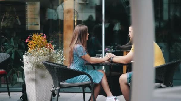 Mattina data della giovane coppia europea innamorata di chiacchierare in caffè all'aperto nel centro della città al rallentatore. Un tizio barbuto seduto a tavola per strada con la sua ragazza. Coppia romantica a pranzo. — Video Stock