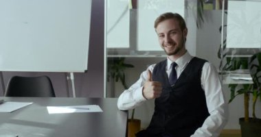 Kendine güvenen işadamı, ofis işyerinde el işaretini gösteren bir kameraya bakıyor. Erkek bağımsız hareket, anlaşma ve iş ile işaret parmağı ile yapılır, başarı konsepti