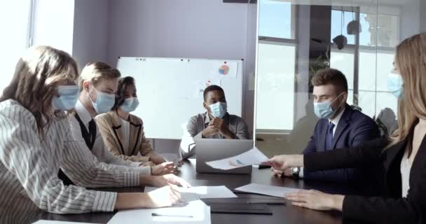 Team van zakenpartners, werknemers zit in functie op conferentie vergadering samen, draagt beschermende medische chirurgische maskers op hun gezicht, communiceert werken in quarantaine, applaudisseert overwinning — Stockvideo