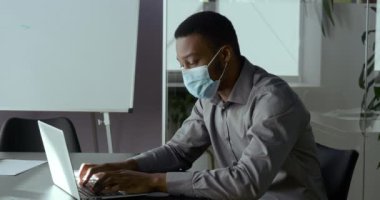 Genç Afrikalı özgüvenli iş adamı yabancı öğrenci laptopta yazıyor, virüs salgını sırasında uzaktan çalışıyor, not defterine not alıyor, internette ödev yapıyor.