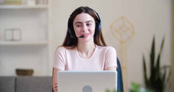Zdjęcie głowy portret młoda tysiąclecia kobieta siedzieć przy stole domu nosić słuchawki rozmowy, konsultując klientów, odległej komunikacji. Rozmowa z klientami przez linię telefoniczną, serwis pomocy, nowoczesna koncepcja technologiczna — Wideo stockowe