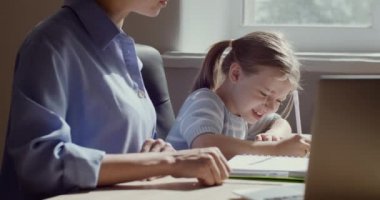 Çocuk kız ve anne aynı masada oturuyor, evde çalışıyor, ödev yapmaktan yorulmuş, matematik problemini çözmek için zorlanıyor. Anne ve çocuk kutlama için beşlik çakıyor. Ders bitti.