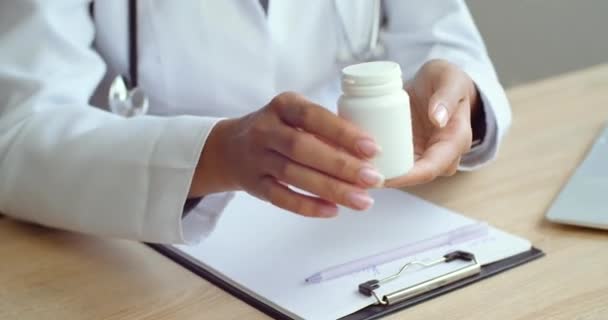 Κοντινό πλάνο των γυναικών χέρια του ιατρικού ειδικού δείχνει μπουκάλι δισκία στον άνθρωπο στον ασθενή, δείχνει το νούμερο δύο με τα δάχτυλά του, συνταγογραφεί για να πάρει το φάρμακο στον άρρωστο άντρα, έννοια της επίσκεψης στο νοσοκομείο — Αρχείο Βίντεο