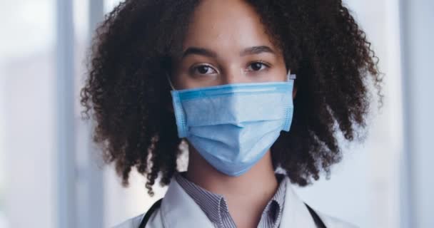 Porträt glücklich lächelnder Afro-Wissenschaftlerin, die nach der Coronavirus-Pandemie ihre schützende medizinische Gesichtsmaske ablegt. Junge kaukasische Amerikanerin genießt das Ende der Covid-19-Pandemie. Virenschutzkonzept — Stockvideo