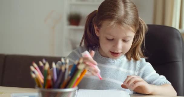 Portret van leuke slimme basisschool kind meisje leren schrijven doet huiswerk schildert beeld zitten aan huis tafel, creatieve kleine kleuter tekenen, kinderen basisonderwijs, gelukkige jeugd — Stockvideo