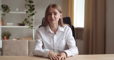 Web kamerasından gülümseyen genç iş kadınının portre görüntüsü el sallayarak selam veriyor. İnternetteki konferans videolarında internetten ya da ofisten uzaktan selamlıyor.