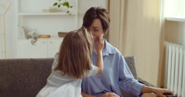 Sevgi dolu küçük bir kız, mutsuz bir anneyi teselli eder, elleri kadın yüzüne uzanan bir kız çocuğu, gülümseyerek dudaklarını gerer, anne teselli eder zor durumlarda sarılmayı destekler.