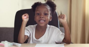Komik, koyu tenli, anaokulu kızı Afrikalı Amerikalı bayan duygusal konuşuyor, mutlu yüz ifadesi, karışık ırk çocuğu hareketli el hareketleri el hareketleri, resim çizimleri, web kamerasından görüş.