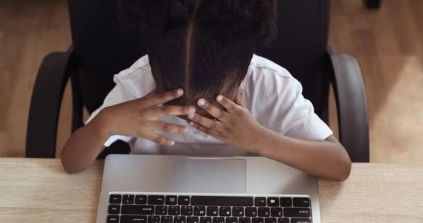 Κοντινό πλάνο λίγο Αφροαμερικανός εθνοτική κορίτσι κάθεται στο τραπέζι δακτυλογράφηση στο πληκτρολόγιο laptop αίσθημα θυμωμένος πρόβλημα ερεθισμού. Μεικτή φυλή θηλυκό παιδί κρατώντας το κεφάλι της από το άγχος σκληρή εργασία, top view — Αρχείο Βίντεο