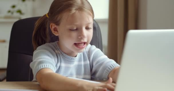 Petite écolière mignonne assise à l'ordinateur portable tapant avec les doigts féminins sur le clavier, étudiant à distance à la maison, écoles fermées pour quarantaine pendant la pandémie de virus, bébé obtient des connaissances en ligne — Video