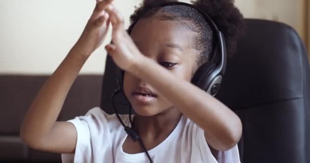 Portrét malé podnikatelky student africké americké dítě dívka nosí sluchátka mikrofon aktivně mluví v webové kamery emocionálně mluví gestikuluje ukazující ruce ve vzduchu počítá na prstech — Stock video
