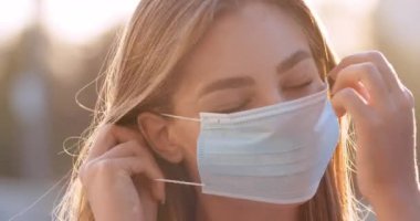 Karantinada, sokakta duran, tıbbi maskeli, beyaz, güzel bir kadının portresini yakından çek. Gülümseyen mutlu kız, kadın yüzü takıyor. Sağlık güvenlik önlemleri kavramı