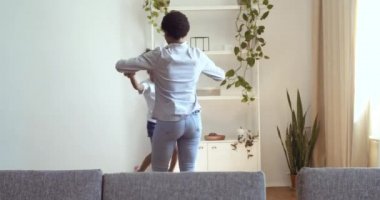 Aktif, mutlu bir Afrikalı anne ve küçük tatlı bir kız çocuğu. İki insan dans ederek evde zıplıyor. Kaygısız, komik, siyah bir aile annesi.