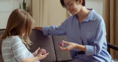 Genç anne, kanepede oturan sevimli küçük anaokulu kızıyla oynuyor iplik toplarıyla sepete bakıyor, birbirlerine oyuncaklar fırlatıyor, birlikte eğleniyorlar, kadın ve çocuk evde vakit geçiriyorlar.