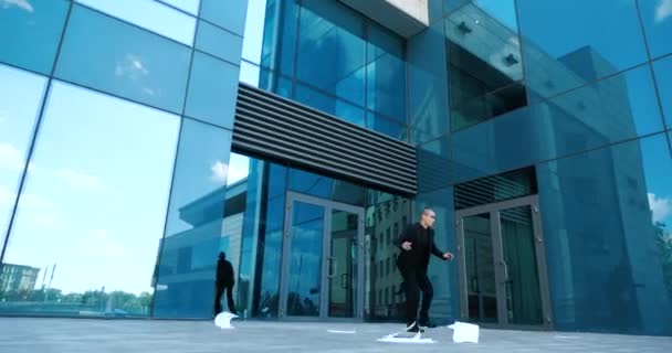 Kantoormedewerker haast zich naar kantoor te laat voor de vergadering, verliest druppels documenten op de stoep op straat in de buurt van business center, wind blaast papieren aan de zijkant draagt weg, manager haalt bestanden van de grond — Stockvideo