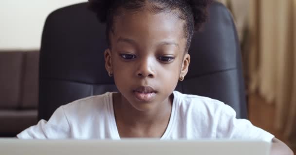 Ragazzina africana divertente guardando la fotocamera web o lo schermo del computer portatile seduto a casa, ragazzo carino parlando facendo videochiamate online o registrando vlog divertirsi. Ritratto di bambino di razza mista prescolare — Video Stock