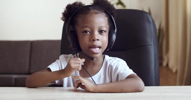 Webcam 'den küçük şirin bir kız çocuğu Afrika kökenli Amerikalı çocuk mikrofon takıyor öğretmenle uzaktan yakından iletişim kuruyor internetten e-öğreniyor, karantina salgınında yalnızlık çekiyor. — Stok video