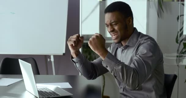 Portret van een dolblij Afrikaans-Amerikaanse zakenman op zoek naar laptop scherm, opgewonden door ongelooflijk goed nieuws. Emotionele etniciteit uitvoerende vieren ontvangst aangetrokken investeringskennisgeving — Stockvideo