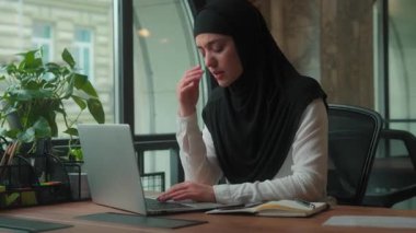 Müslüman iş kadını kadın tesettüre girmiş migren ağrısı çeken iş kadını. Gözler ağrıdan rahatsız. Ofisteki bilgisayarın tahriş olmuş gözünden rahatsız.