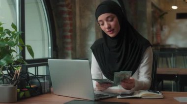 Mutlu gülümseyen Müslüman İslami kadın tesettür bankası çalışanı başarılı iş kadını para sayan başarılı iş kadını para kazanan para kazanan finansal kazananlar maaş şirketinin şirket bütçesini hesapla