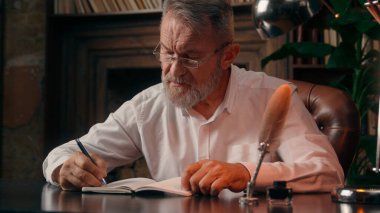 Kendinden emin, yaşlı, beyaz, olgun bir erkek kamera önünde el ele tutuşmuş ofis işadamı yakışıklı, yaşlı çalışan portresi liderinin içindeki iş adamına bakıyor.