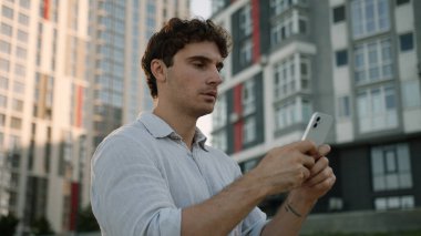 Ciddi bir Kafkasyalı elinde cep telefonu, akıllı sohbet internet uygulaması, dalgın işveren, şehir iş adamı, açık hava sosyal medya sitelerinde cep telefonu ağı mesajları yazıyor.