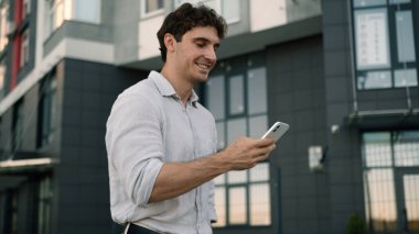 Kafkasyalı bir adam cep telefonuyla yürür sosyal medya teknolojisi ağları internet çalışanı, erkek işadamı, iş adamı şehir dışında cihaz saklayan cep telefonu işçisi.