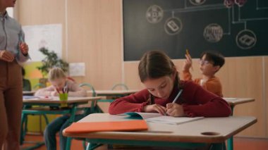 Okula çok ırklı çocuklar ilköğretim eğitimini öğreniyor. Kafkas çocuk kolunu kaldırıyor. Kadın öğretmen için yardım istiyor.