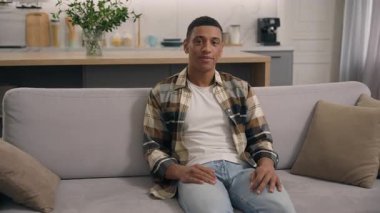 Kaygısız, mutlu, mutlu, Afro-Amerikalı, gülümseyen, kanepede oturup rahatlayan, klima keyfi yapan, erkek, ev kredisi konsepti.