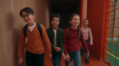 Dört mutlu, çok ırklı çocuk çeşitliliği sınıf arkadaşları beyaz kız Afrikalı Amerikalı erkek öğrenciler sınıfa giriyor koridor okul koridorunda yürüyorlar derse girmek için acele edin.