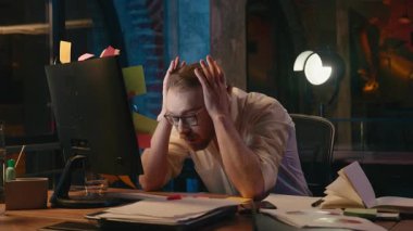 Karanlık gece ofisindeki stresli iş adamının gece vakti bilgisayarla başı dertteymiş. Yorgun iş adamı aşırı çalışmış. Çevrimiçi zorluklardan muzdarip.