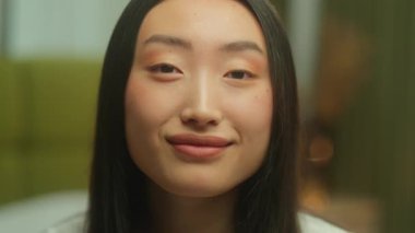 Yakın plan Asyalı kız modeli stüdyoda kameraya gülümsüyor Japon bayan etnik kadına bakıyor Çinli bayan kız arkadaş gülümsüyor mutlu, mutlu, tasasız, mutlu bir ev kadını.