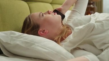 Kafkasyalı bir kadın yatakta uzanıyor, cep telefonu görüşmelerini tartışıyor, sinirlenmiş bir şekilde yatak odasında akıllı telefon konuşmaları yapıyor, sinirli kız uyanıyor, gergin bir şekilde tartışıyor, kavga ediyor.