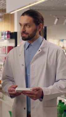 Olgun, yaşlı bir eczacı eczaneden ilaç almaya yardım ediyor. Kalp hapları, sağlıklı vitaminler, güler yüzlü erkekler. Müşterinin sağlık hizmetlerine yardım eden doktor.