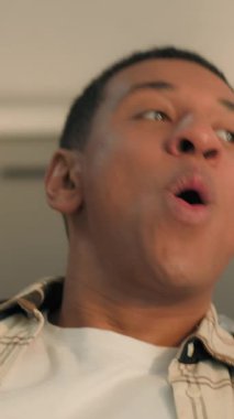 Gülümseyen mutlu Afro-Amerikan adam evinde dinleniyor tatmin oluyor erkek ev sahibi pozitif nefes alıyor rahat kanepenin yerini değiştiriyor yeni eve taşınıyor klimanın tadını çıkarıyor.