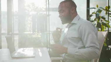 Güneş ışığında dizüstü bilgisayarıyla dans eden mutlu Afro-Amerikalı iş adamı hareketli neşeli yetişkin iş adamı porselen dansı dinliyor zaferi kutluyor, neşe içinde eğleniyor.
