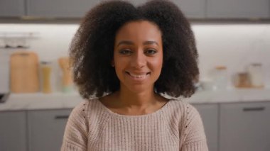 Mutlu portre mutlu gülümseme pozitif kaygısız Afrikalı Afro-Amerikan kadın güzel kız neşe dolu kadın kameraya yakından bakan ev sahibi kadın ev sahibi ev mutfağında tatmin olmuş vesikalık fotoğraf.