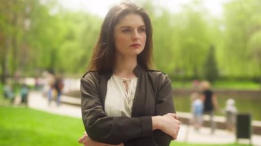 Kendine güvenen beyaz kadın kollarını kavuşturup kameraya bakıyordu. Ciddi kız iş kadını parkı. Güçlü bağımsız lider pozu.