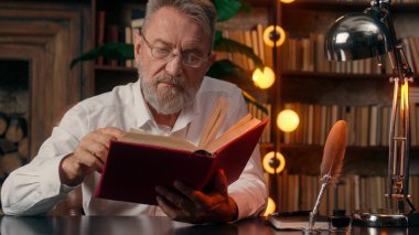 Kendinden emin, yaşlı, beyaz, olgun bir erkek kamera önünde el ele tutuşmuş ofis işadamı yakışıklı, yaşlı çalışan portresi liderinin içindeki iş adamına bakıyor.