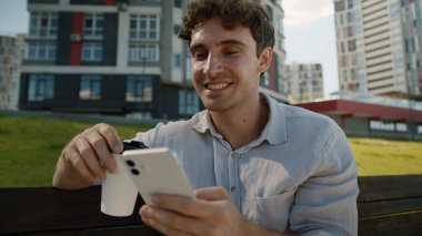 Kafası karışmış Kafası karışık beyaz adam cep telefonu kullanıyor. Akıllı telefon kullanıyor. Haber okuyan erkek öğrenci, kahve içiyor.