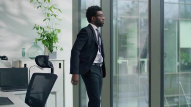 Afro-Amerikalı iş adamı. Pencere kenarında eli cam üzerinde çalışan erkek işçi. Stresli, düşünceli, anksiyete baskısı çeken bir şirket.