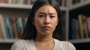 Bayan portresi üzgün Asyalı kız öğrenciyi üzdü. Üniversite kütüphanesinde sıkıntılı bir ifadeyle kameraya baktı. Çaresiz genç bayan başarısız sonuç sınavına üzüldü.