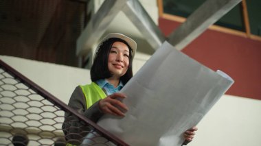 Tatmin olmuş Asyalı Çinli Japon kadın inşaatçı kadın mimar kadın iş kadını güvenlik kaskı mühendisi planlayıcı kız teftiş kağıtları bina projesi