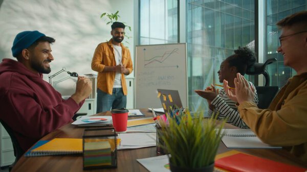 Успешная презентация стартапа в неформальном офисе разнообразная мультикультурная команда неформального бизнеса аплодирует лидеру мужского пола, показывая график роста на доске объявлений о достижениях