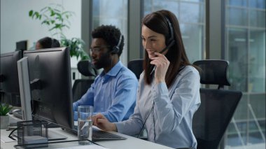 Çağrı merkezi başarısı. Çoklu etnik operatörler bilgisayar yardım hattı hizmet ajansı Kafkasyalı iş kadını yumruğunu sıkma başarılı Hintli Afrikalı iş arkadaşları için ofis kulaklığı çağrı merkezinde çalışıyor.